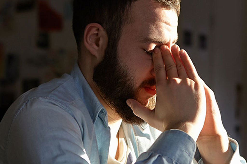Stressed man with face in hands